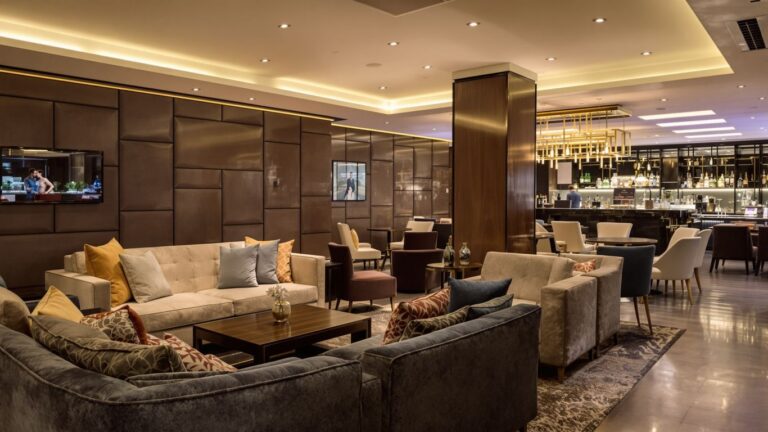 Modern airline lounge with comfortable seating and bar.