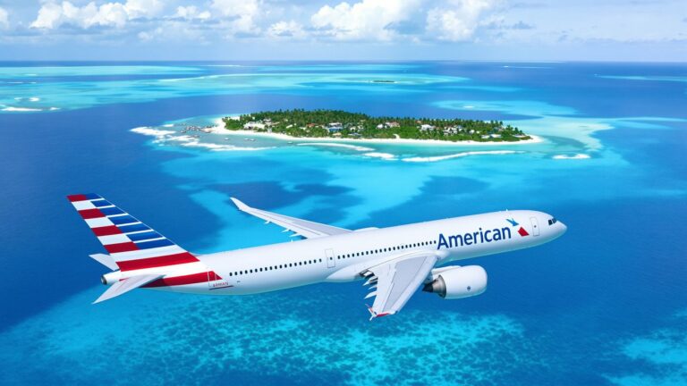 Airplane flying over turquoise water towards Bimini island.
