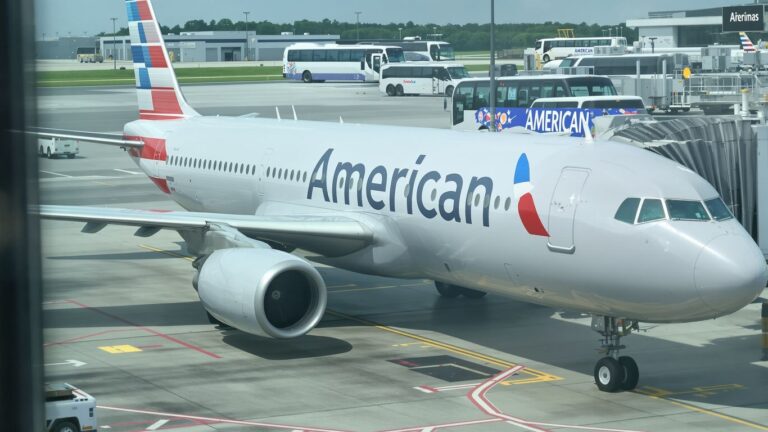 American Airlines plane and branded bus at airport.