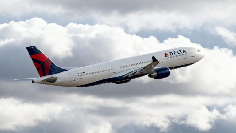 Delta airplane in flight against clouds.