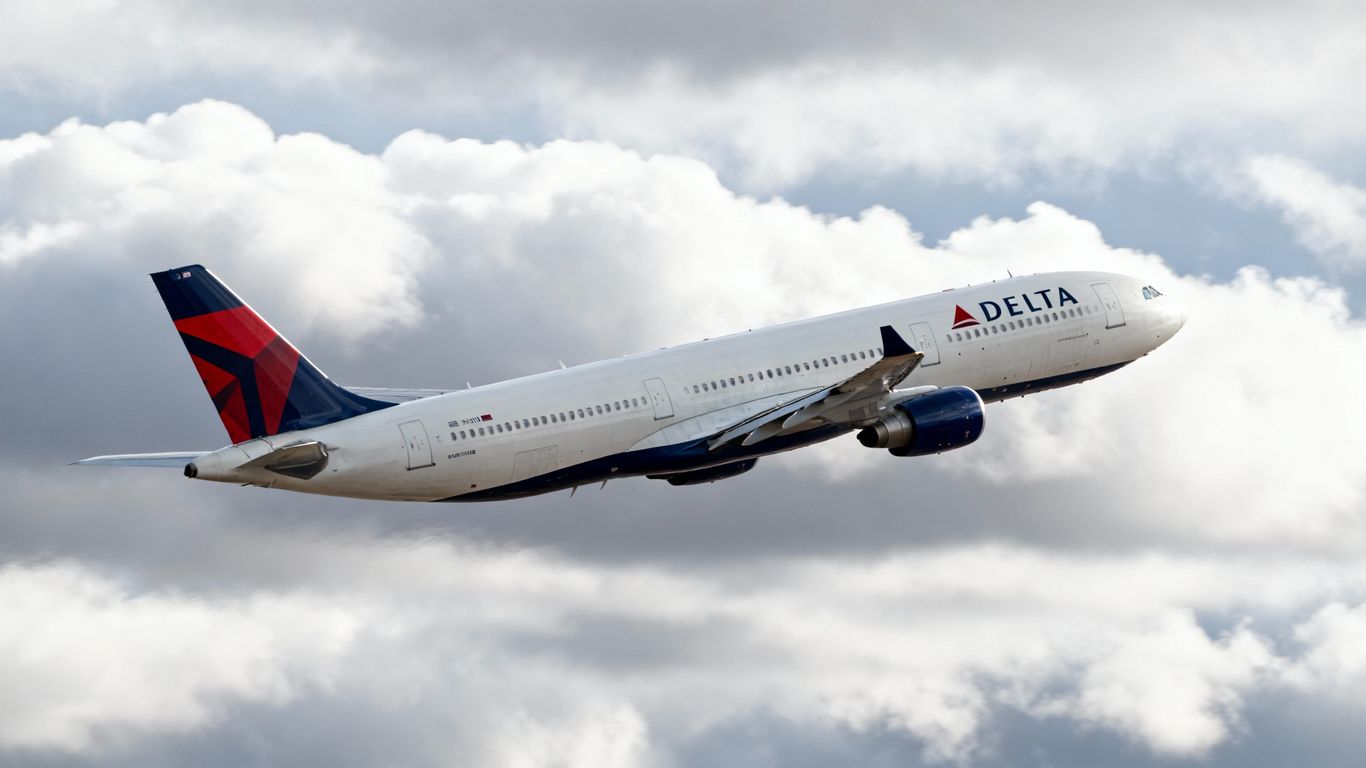 Delta airplane in flight against clouds.