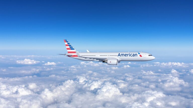 American Airlines plane flying in a blue sky.